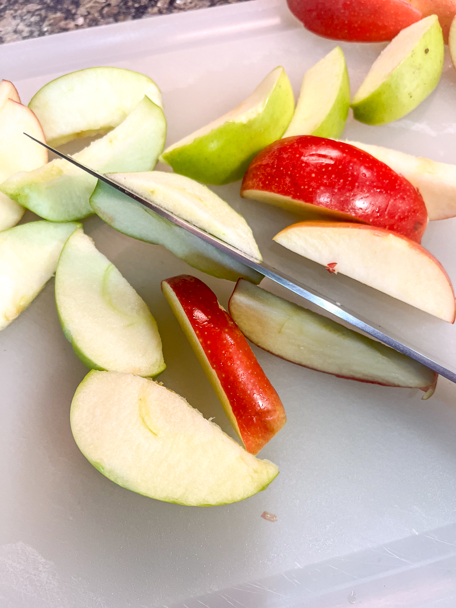 Apple slices being cut in half again to make them thinner.