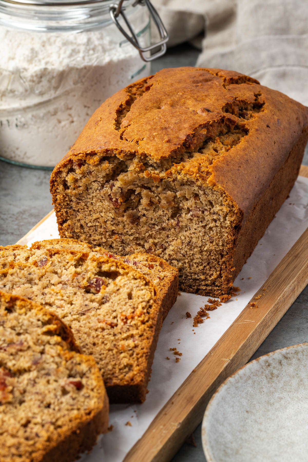 Half a loaf of banana bacon bread with slices leaning over in front.
