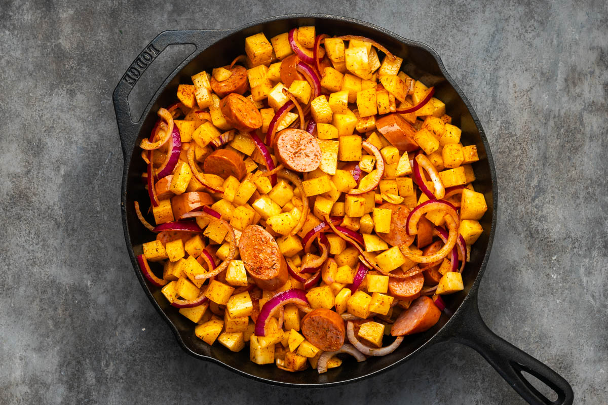Sausage and potatoes mixture added to the skillet to cook.