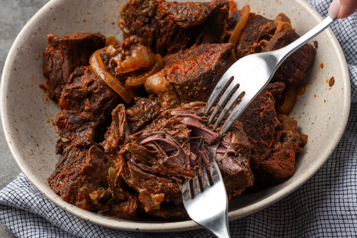 Beef shredded on the pot with two forks. 