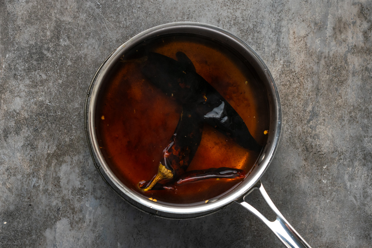 Dried guajillo peppers soaking in hot water.