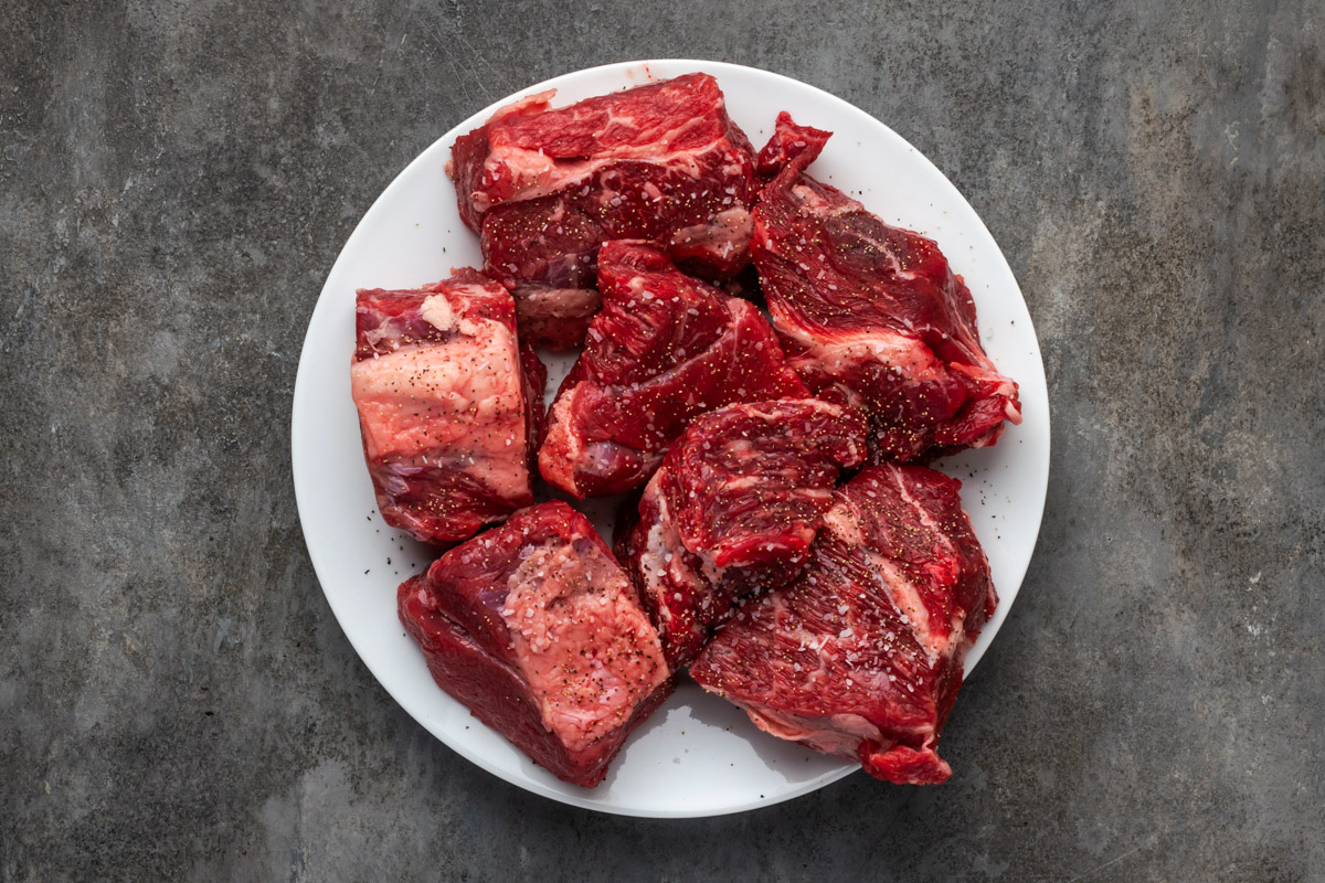 Chuck roast seasoned and cut up on a plate.