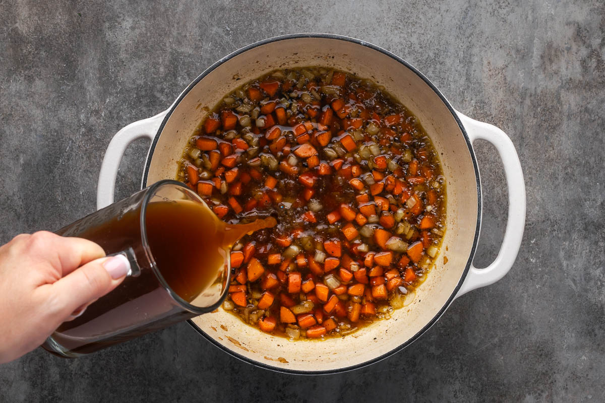 Diced onion, carrots, shallots and beef broth to the pot and cook.