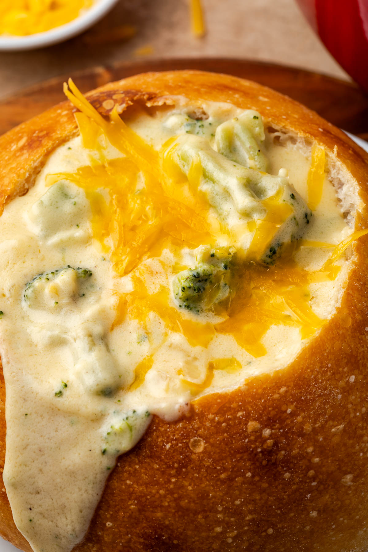 Broccoli cheese soup spilling over a bread bowl.