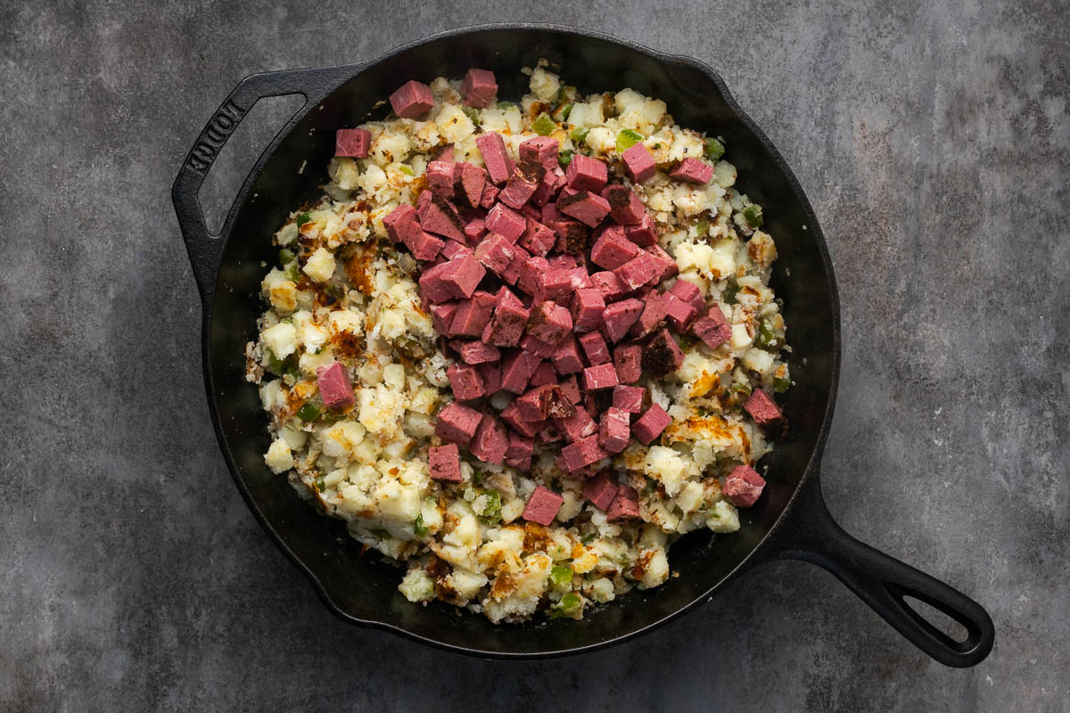 Cubed pastrami added to the skillet.