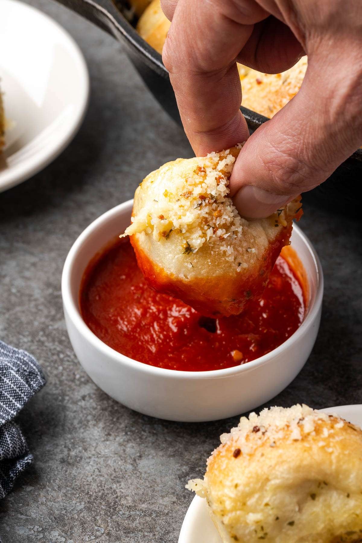 Garlic Parmesan pull apart bread being dipped into marinara sauce.