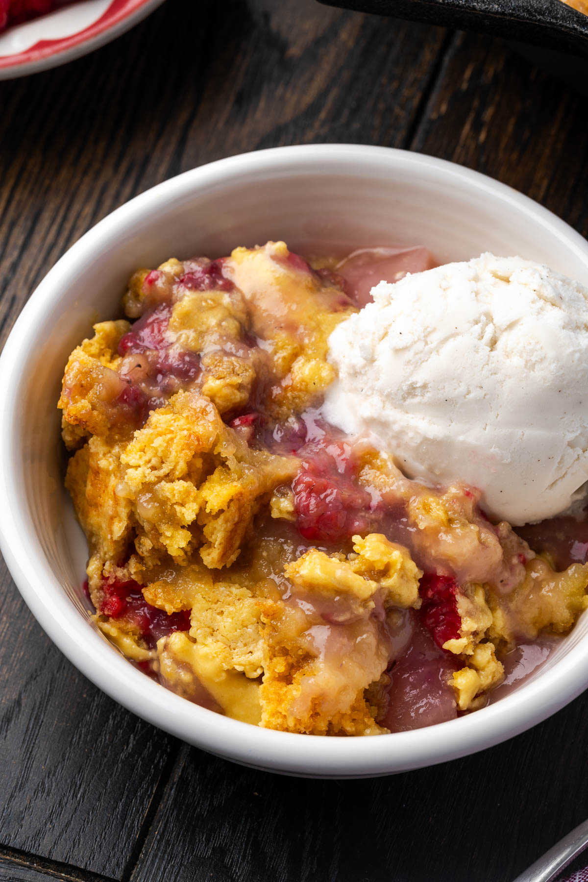 Easy pear raspberry dump cake in a bowl with a scoop of ice cream. 