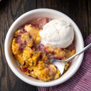 Easy pear raspberry dump cake with ice cream in a bowl.