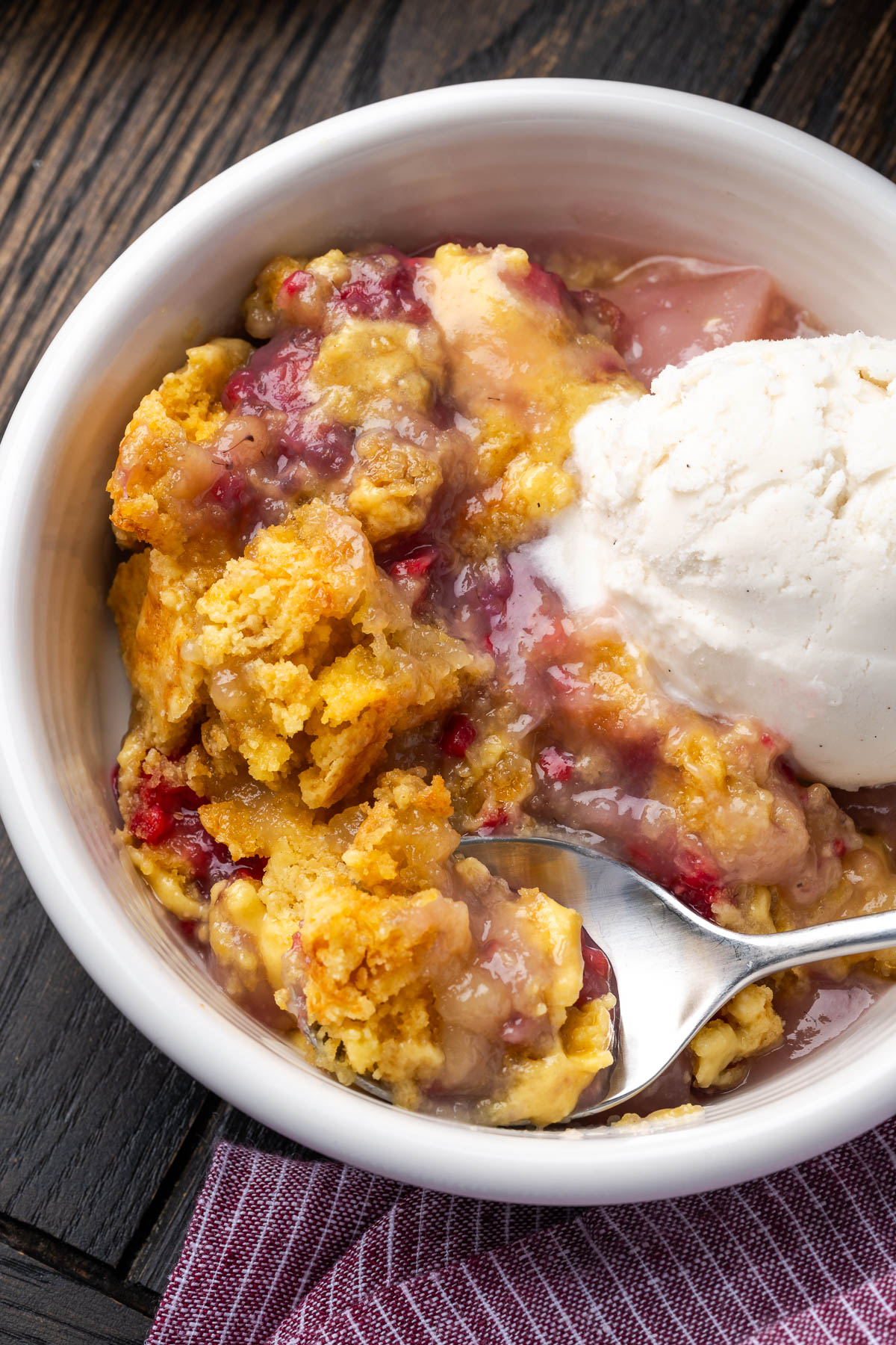 A spoon scooping out some dump cake with raspberry and pears.