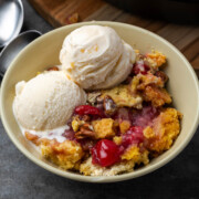 Cherry pineapple dump cake in a bowl with two scoops of ice cream.