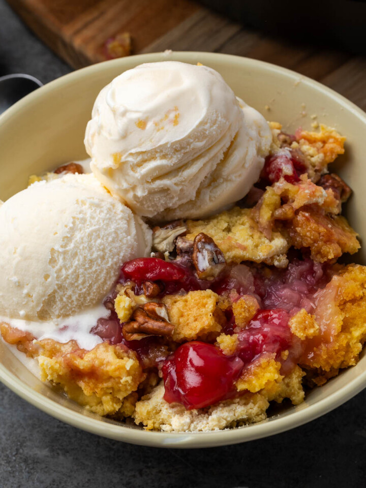 Cherry pineapple dump cake in a bowl with two scoops of ice cream.