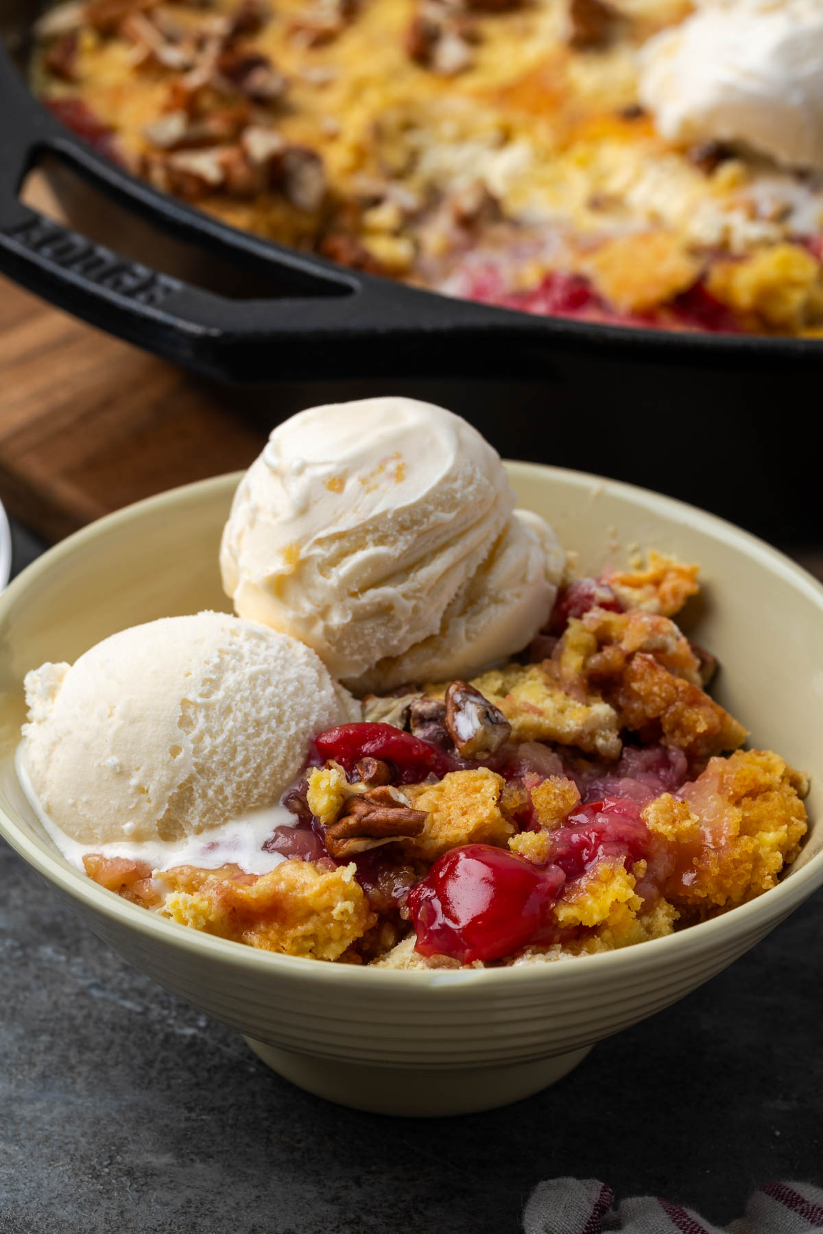 Cherry pineapple dump cake with ice cream in a bowl.