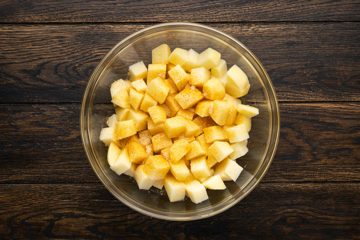 Potatoes, oil and seasoning in a bowl.