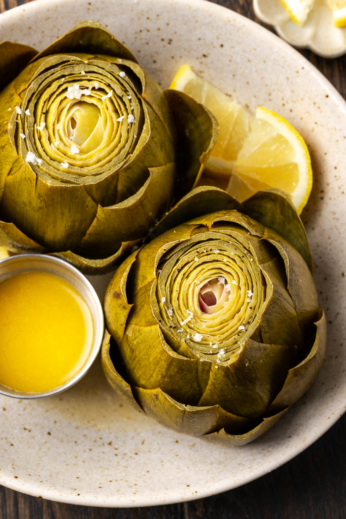 Steamed artichokes on a plate with butter and lemon.