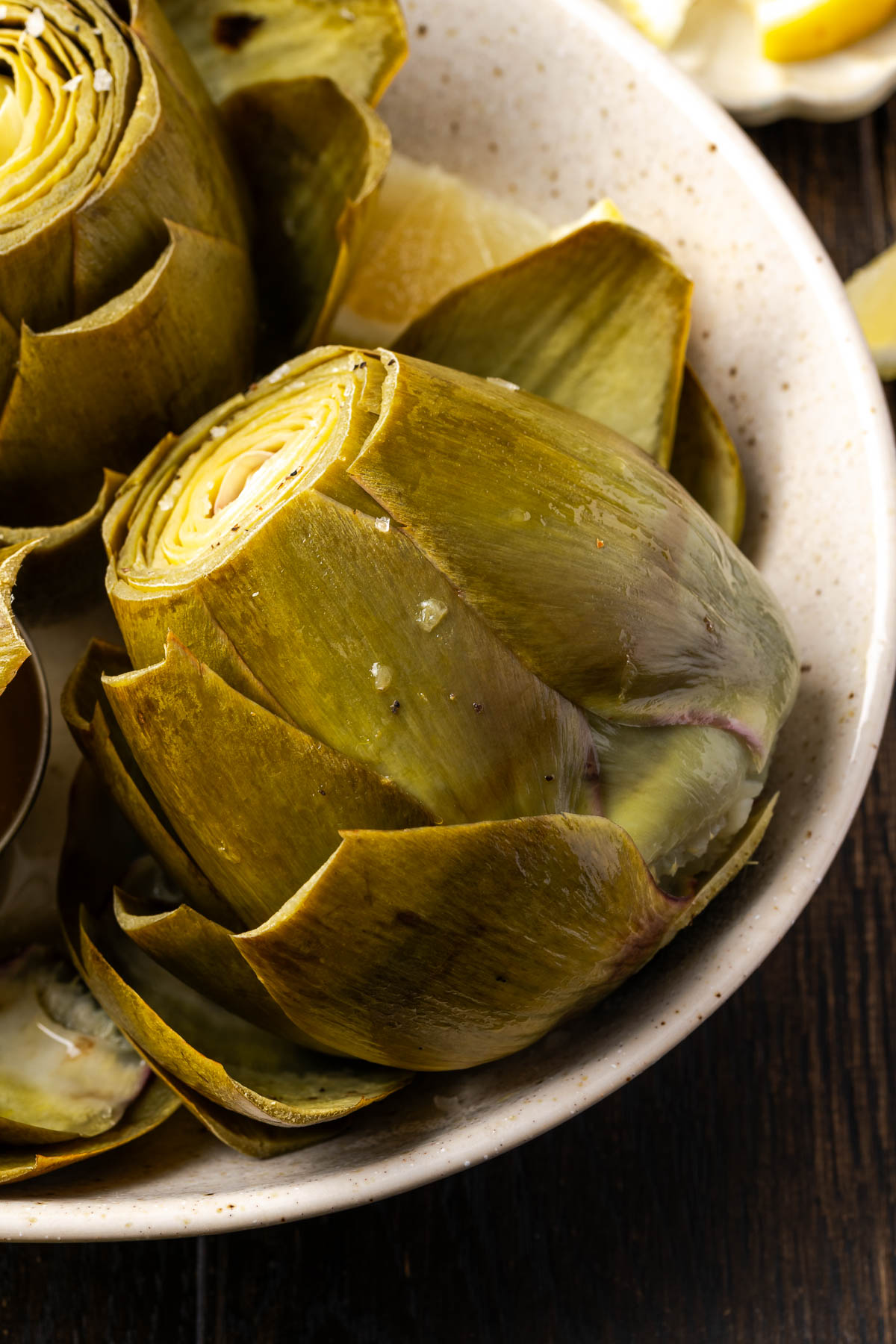 Artichoke leaning sideways on a plate.