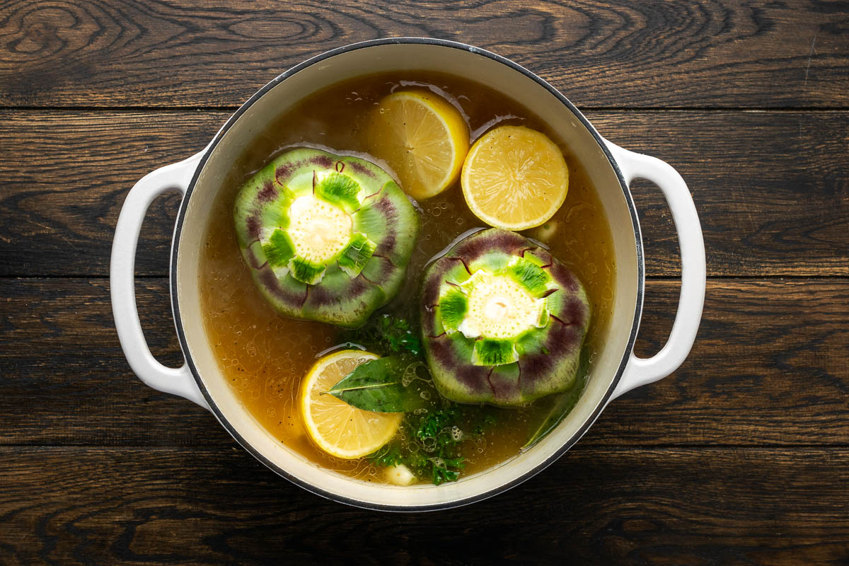 Artichokes placed upright in the dutch oven and covered.