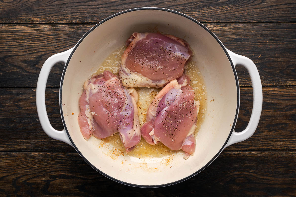 Chicken thighs with salt and pepper in the pan.