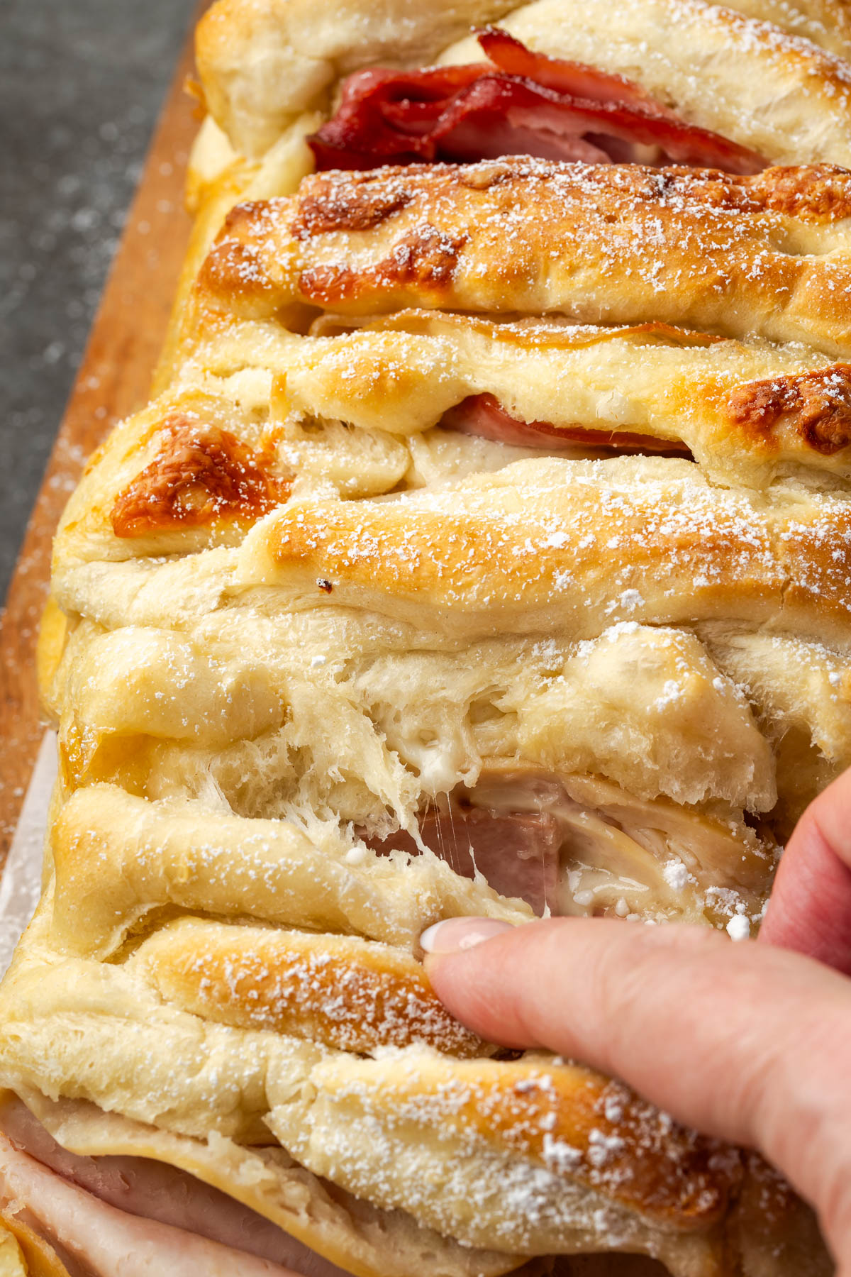 Rhodes dough and ham casserole with a hand reaching to pull a piece apart.