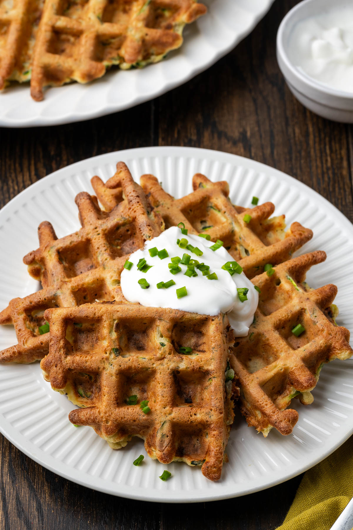 Potato waffles on a plate with sour cream on top.