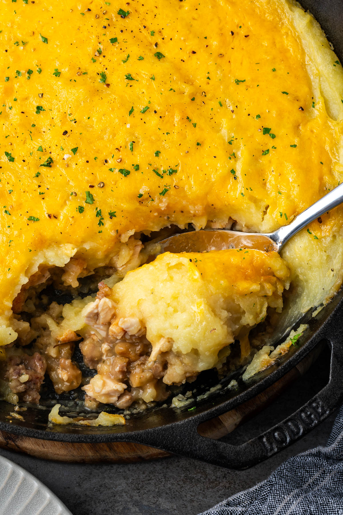 A spoon scooping out some turkey shepherd pie from a skillet.