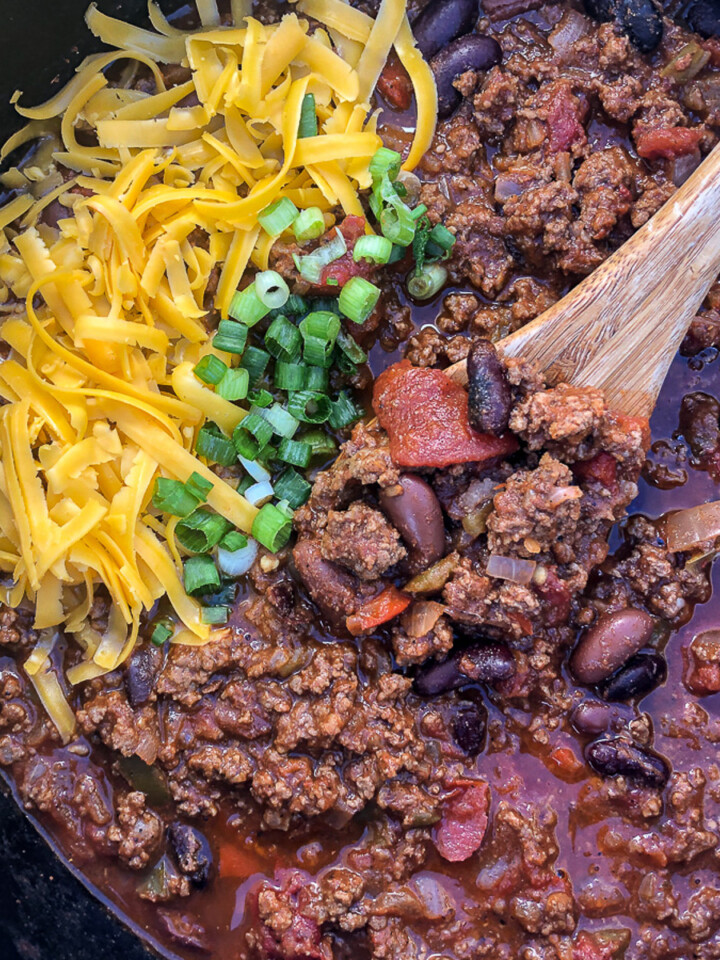 A pot of Dutch oven chili with a wooden spoon in the pot.