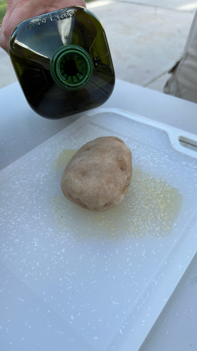 Adding oil to the outside of a potato.