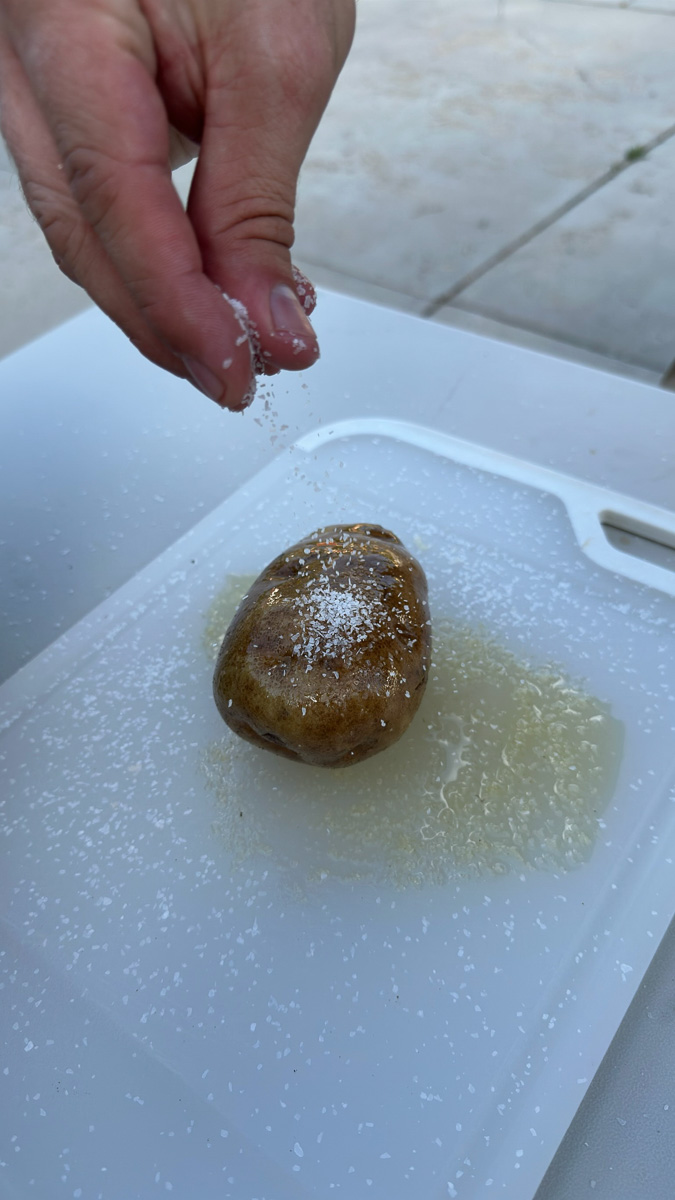 Coating a potato in olive oil and salt.