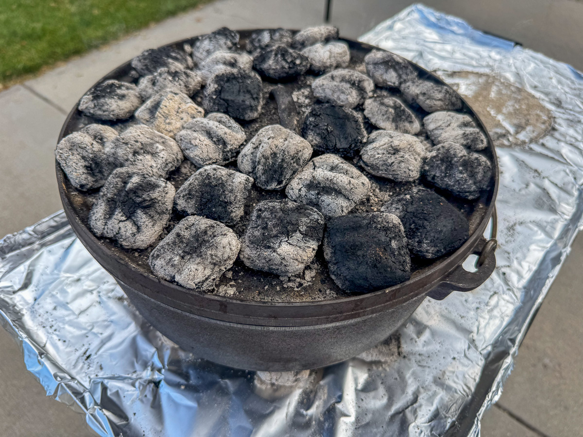 Dutch oven topped with lid and coals.