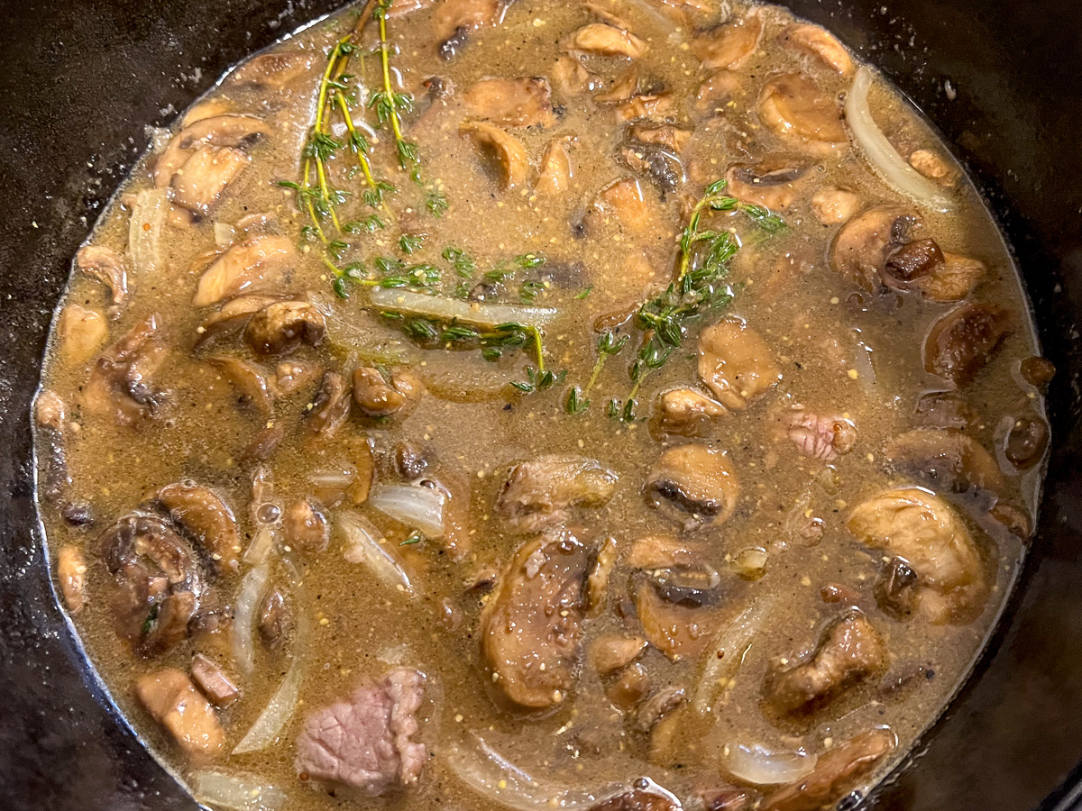 Beef and vegetables added to the pot with the broth.