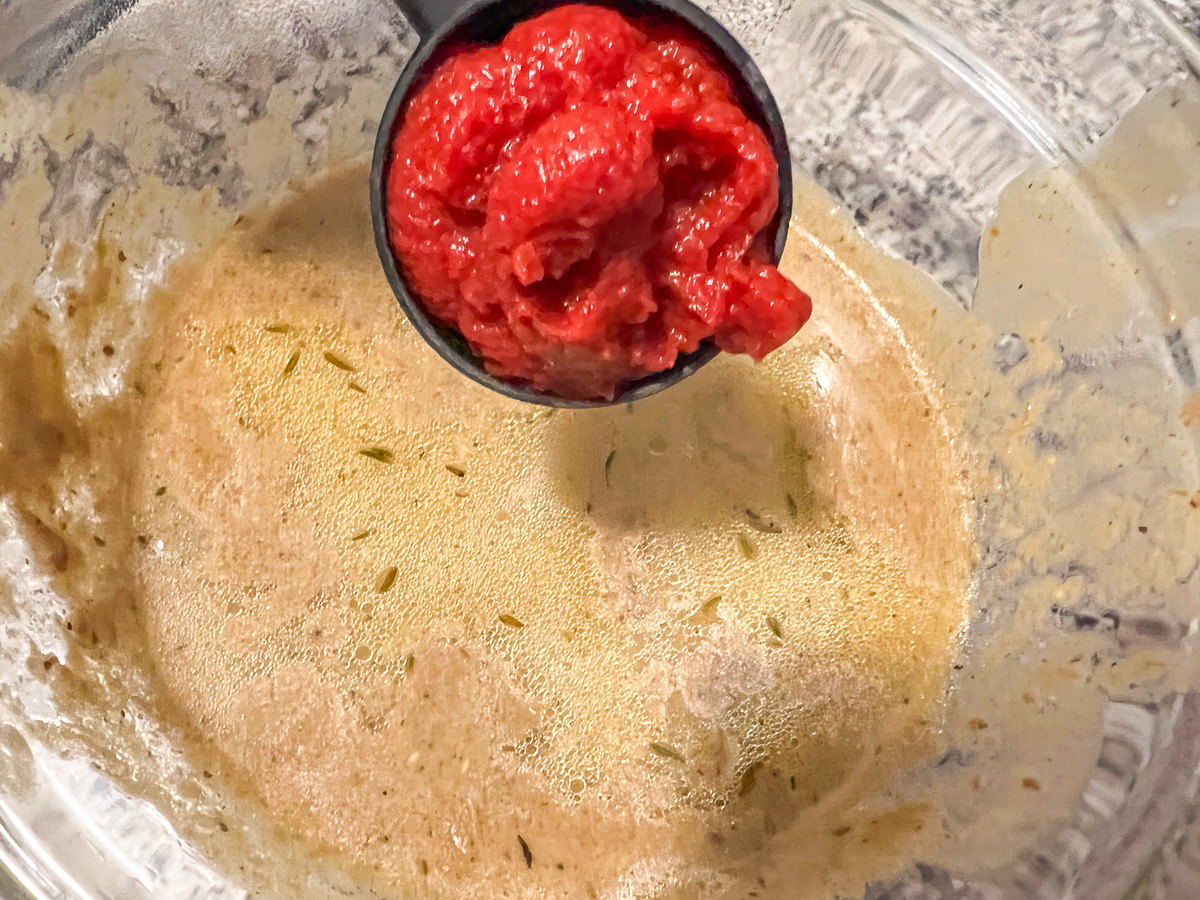 Adding the tomato paste to the beef stroganoff. 