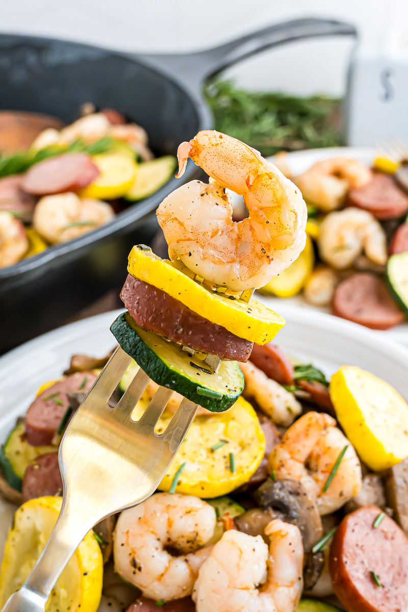 A fork holding some shrimp and veggies in the air.