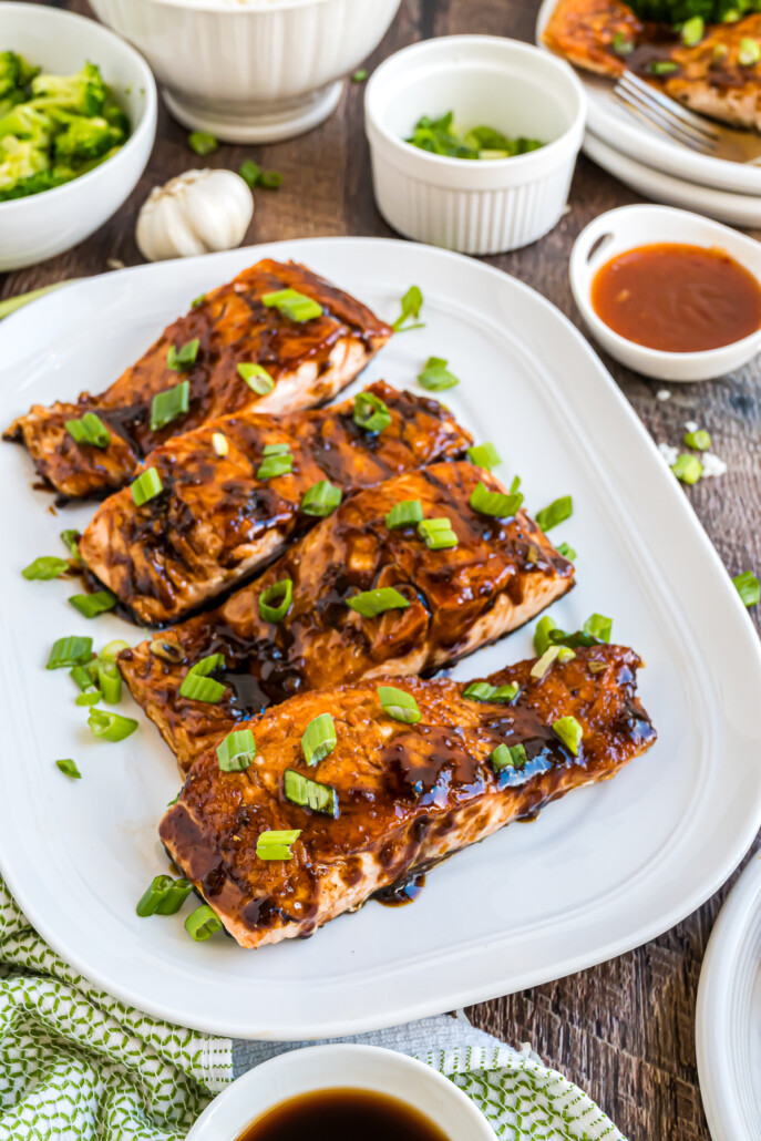Thai chili and balsamic pan-seared salmon on a plate with green onions on top.