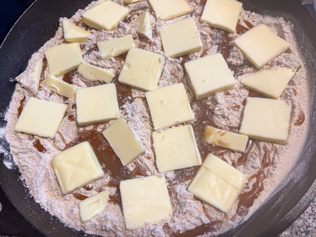 Slices of butter placed over the caramel and cake mix.