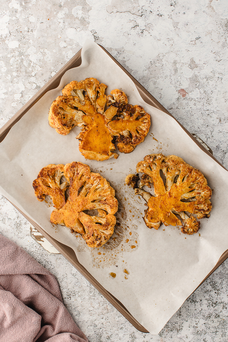 The cooked cauliflower steaks transferred to a prepared baking dish.