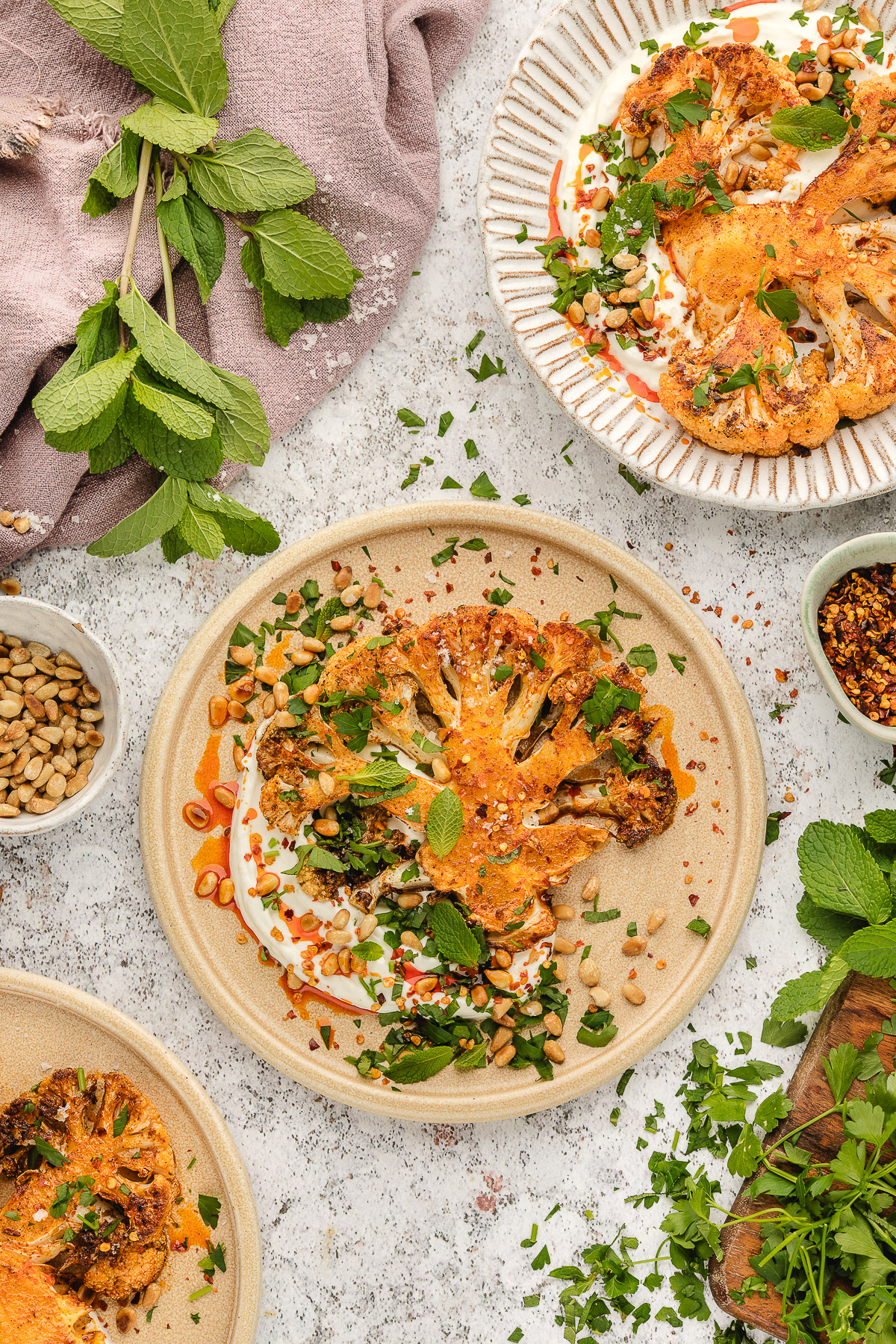 Roasted cauliflower steaks topped with fresh herbs and pine nuts.