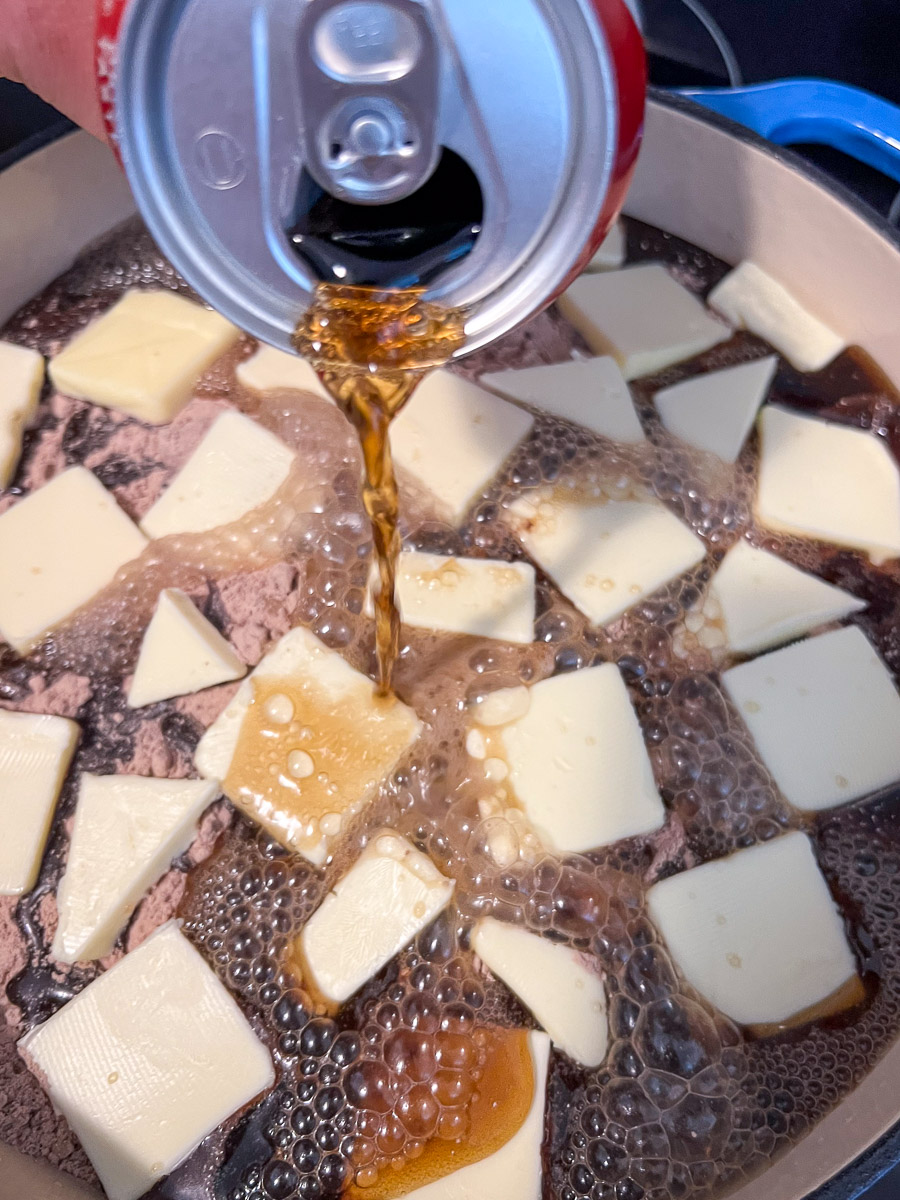 The can of cola is being slowly poured over the cake.