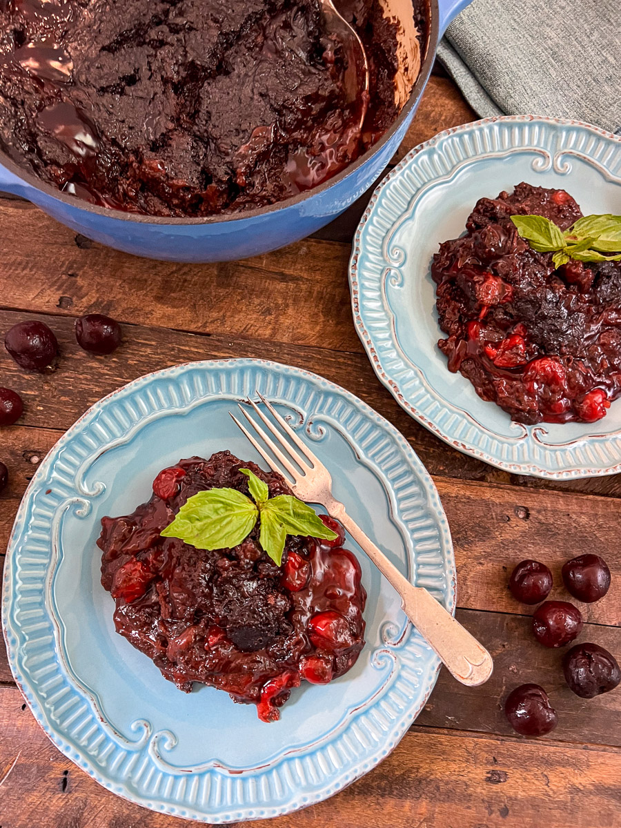 Image of cola chocolate cherry cake pated on two blue plates garnished with fresh mint.
