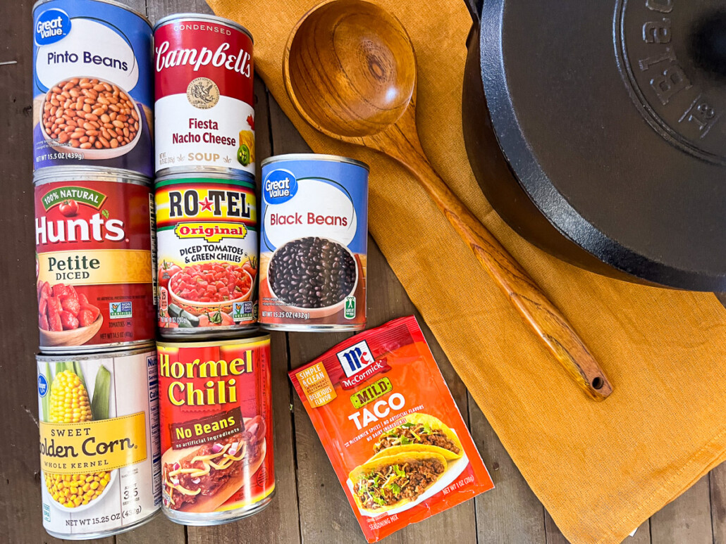 Canned ingredients to make Dutch oven 7 can soup: pinto beans, diced tomatoes, sweet corn, fiesta nacho cheese, Rotel, no beans chili, black beans, and mild taco seasoning packet.