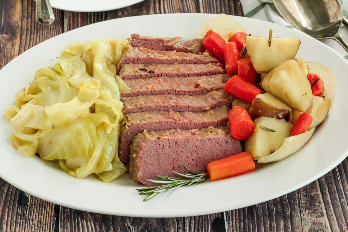 Dutch oven corned beef on a plate with cabbage and vegetables. 