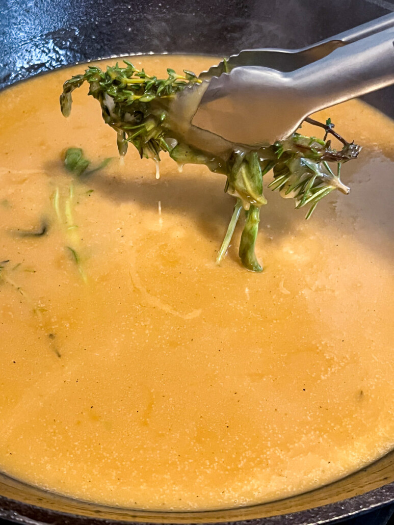 Fresh herbs being removed from the gravy.