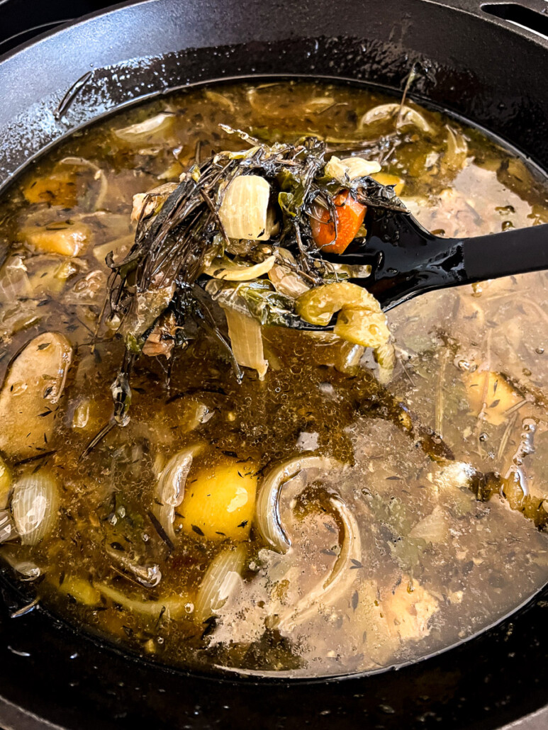 Produce and herbs being removed from the pan drippings in the cast iron skillet.