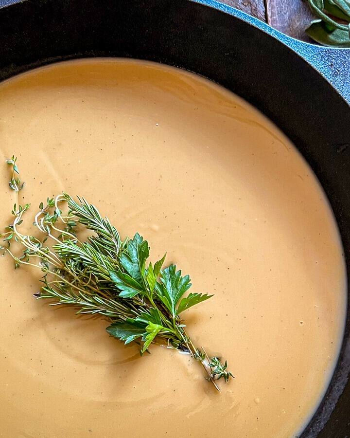 Close up of turkey gravy in the skillet garnished with fresh herbs.