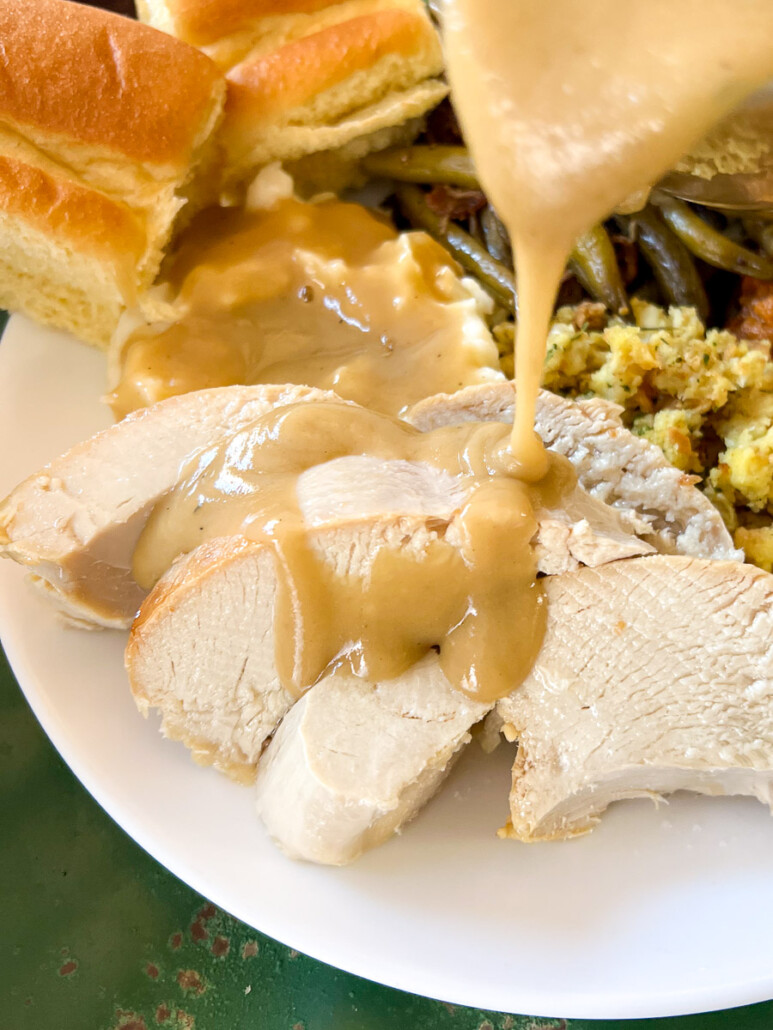 Turkey gravy being over sliced turkey breast.