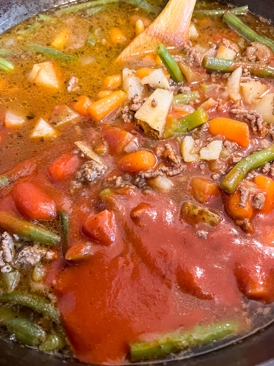 Tomato paste being stirred into the stew.