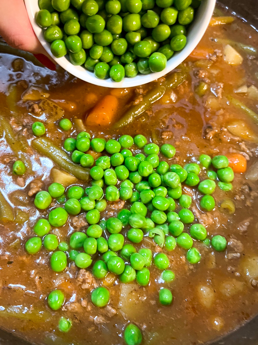 Peas being added to the stew.