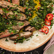 Skillet ribeye steak with chimichurri sauce on a plate.