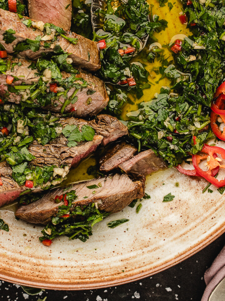 Skillet ribeye steak with chimichurri sauce on a plate.