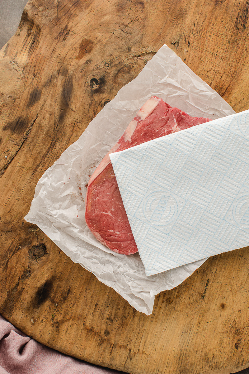 Patting the steak dry the with paper towels.
