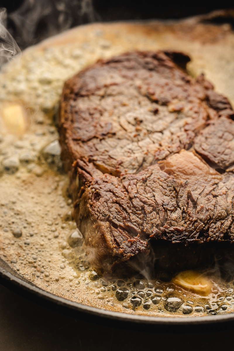 The steak on the skillet over oil.