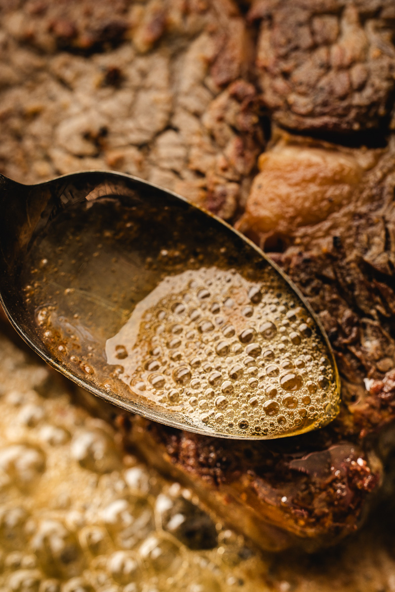 Spooning the butter over the steak.